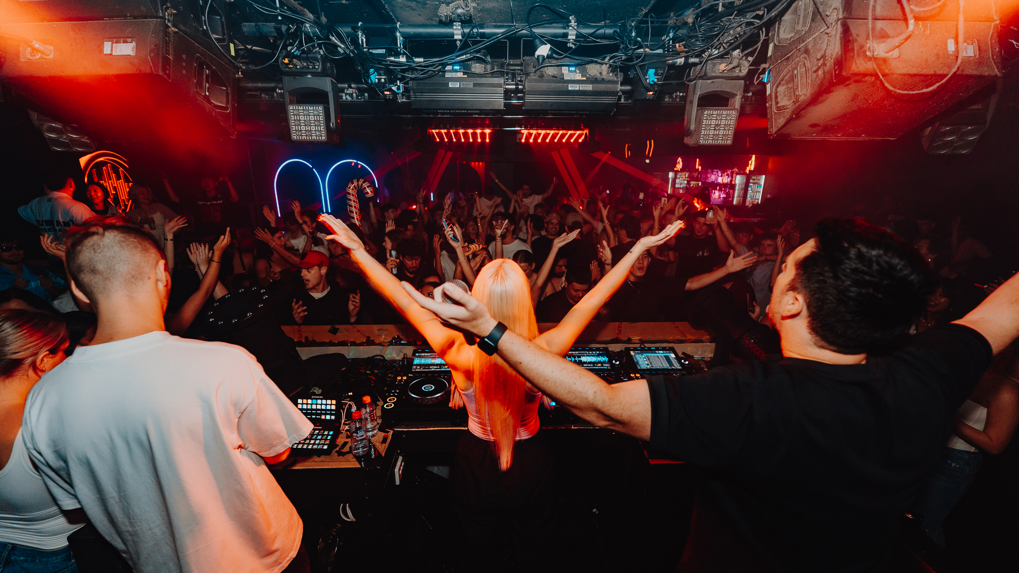 DJ with arms raised at decks, crowd reaction Gold Coast